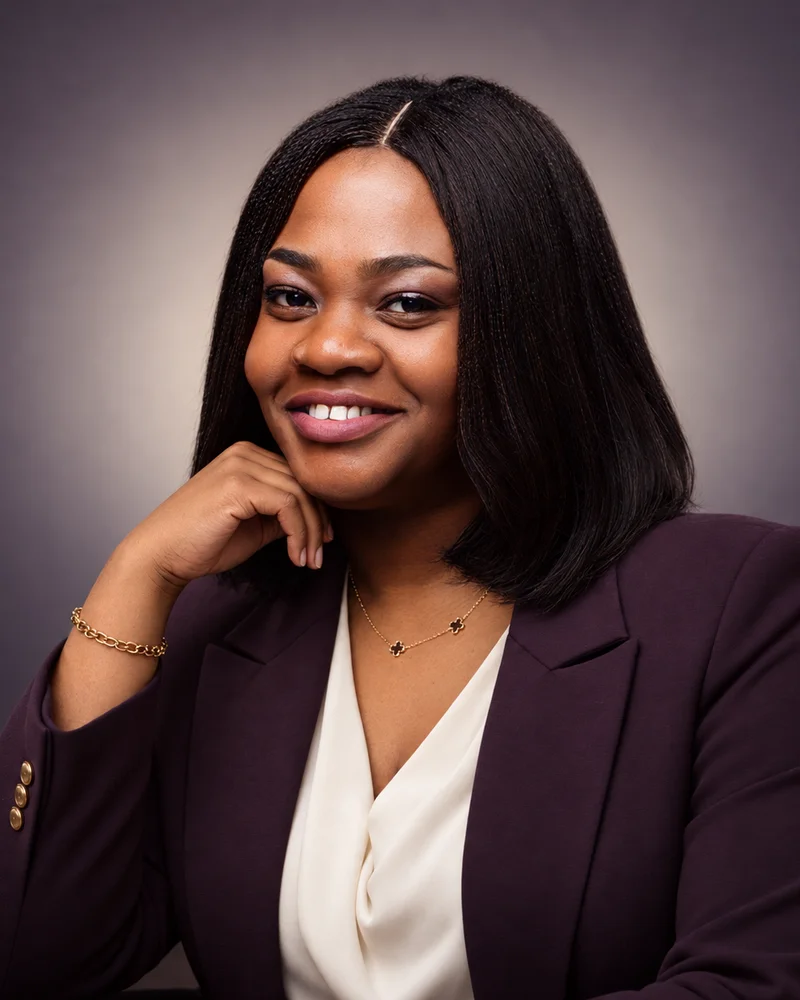 Christiana Essie Sagay, Counsel and Founder of Chressa Law, seated in a plum blazer and cream blouse against a soft violet ground.